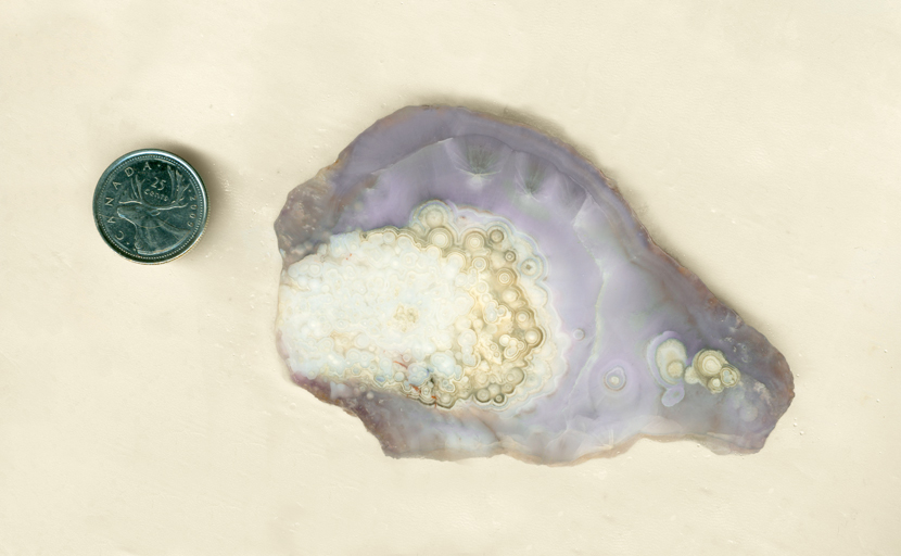 Slab of purple and violet Luna Agate from Mexico, with a colorful background and bright orbs in the foreground.