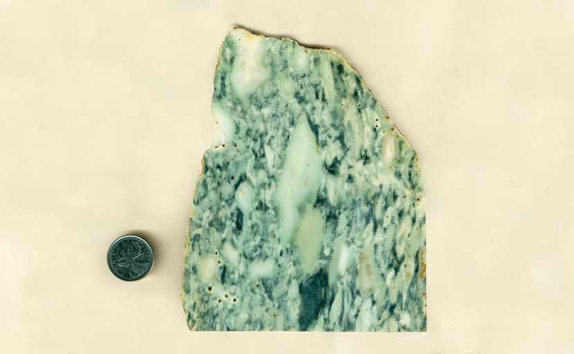 A slab of Vert Antique Marble, with blue-green running markings and brown dots.