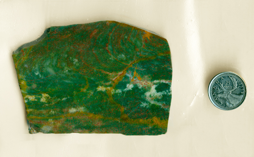 Slab of fancy Jasper from India, green with spots and circles of red and yellow, and cloud patterns of white.