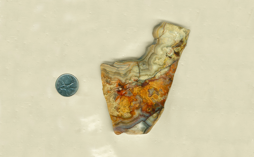 Irregularly shaped slab of Crazy Lace Agate from Mexico, with a blue stripe along the bottom, orange in the center and yellow on the top, covered with lace and flower patterns.