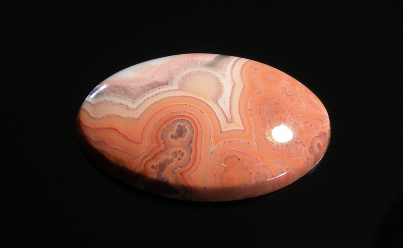 Freeform polished Fairburn Agate cabochon, orange and pink patterns of swirls and orbs.