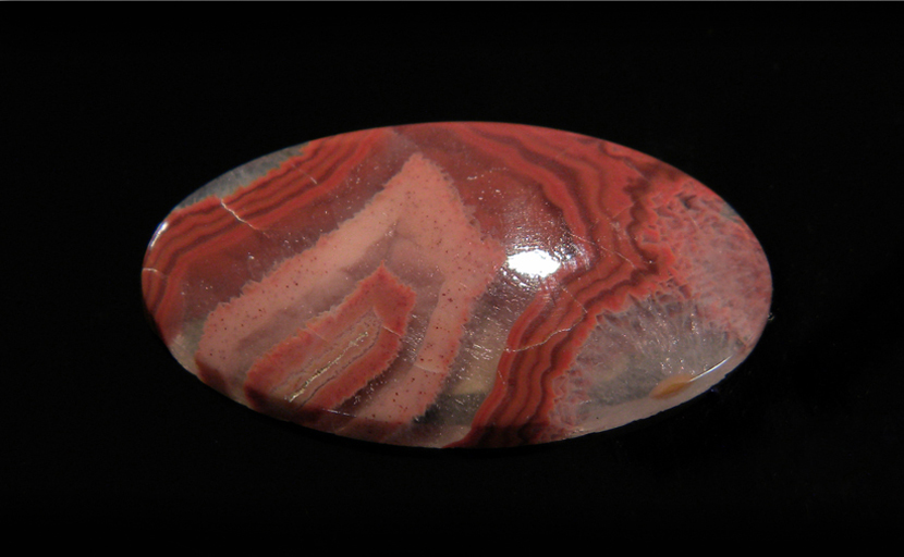 Calibrated oval polished Fairburn Agate from Nebraska or South Dakota, with concentric pink and red stripes suspended in clear chalcedony.