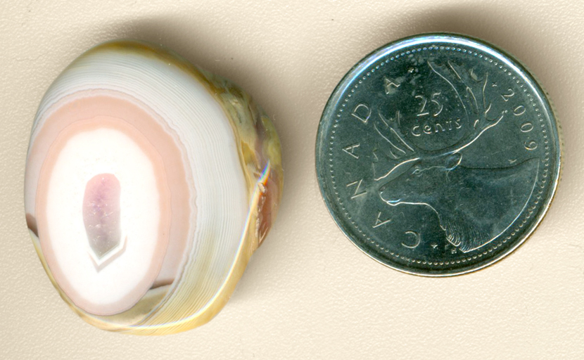 Pastel pink patterns, spaced between white concentric lines, all in a freeform polished Australian Agate.