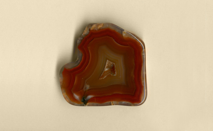 A freeform polished Coyamito Agate from Mexico, with a strong red pattern and a central crystal vug.