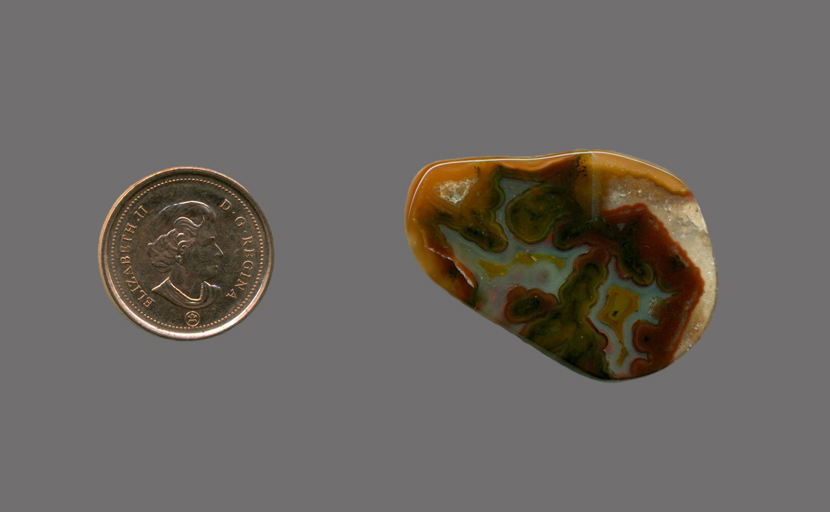 A polished freeform Fortification Agate from Mexico, with bright green and blue colors trapped in brown and orange barriers.