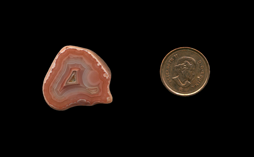Freeform polished Fortification Agate from Mexico, with pink and bluish layers and an inner pocket of druzy crystals.