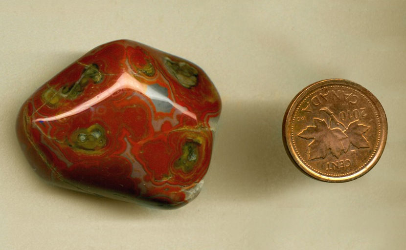 Freeform, polished tumbled Fairburn Agate from Nebraska or South Dakota, with white crystals covering the back and red and blue patterns all over its face.