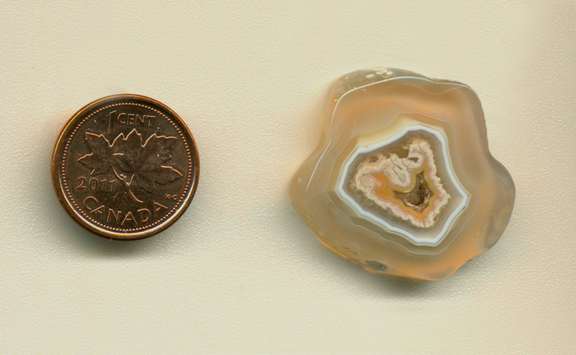 Freeform polished Coyamito Agate from Mexico, translucent with an irregular pink and white fortification pattern in the center, enclosing a pocket of druzy.
