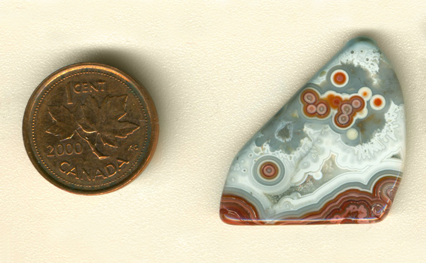 Freeform polished Crazy Lace Agate from Mexico, with red and orange eye patterns in a gray and white sky over a red and pink ground.