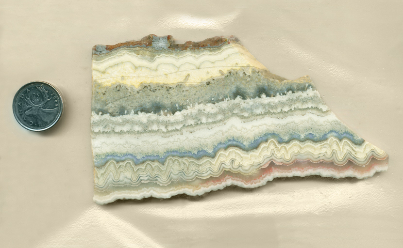 A slab of Dogtooth Lace Agate from Mexico, with pink, yellow and blue zigzag, lace and wavy patterns in parallel lines.
