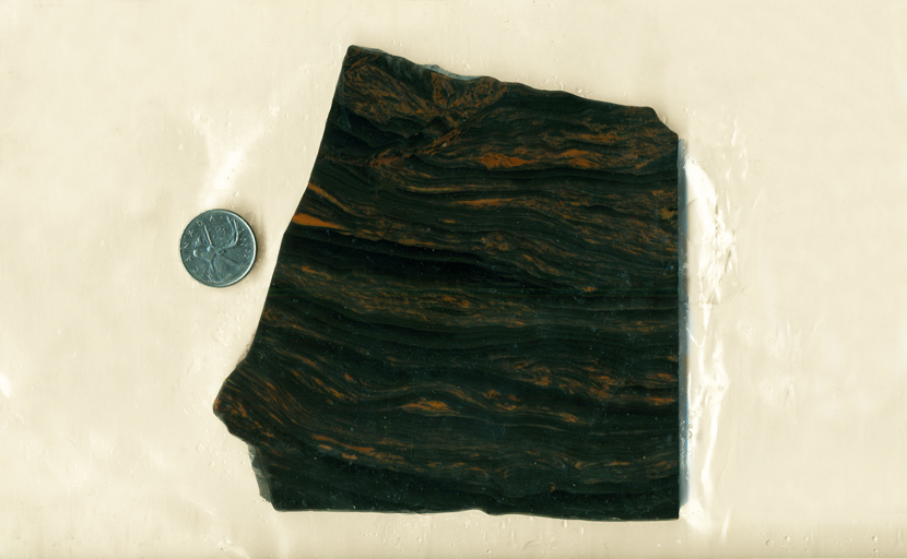 Slab of black obsidian with dark brown swirls against the translucent background.