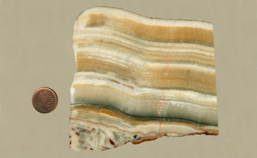 Onyx slab with honey-colored and white stripes, arranged on top of a darker stripe and reddish patterns underneath it.