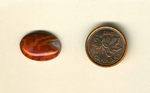 Calibrated oval polished Fairburn Agate cabochon from Nebraska or South Dakota, with simple circular and lumpy shapes of orange and red.
