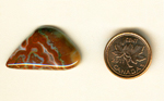 Freeform polished Fairburn Agate cabochon from Nebraska or South Dakota, with red striped patterns, punctuated by blue and white details.