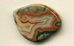 A freeform Fairburn Agate, with a concentric red fortification pattern, surrounded by green orbed patterns.