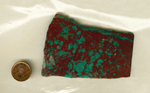 A slab of Cuprite and Malachite from Arizona, with bright green spots on a reddish brown surface, and one stripe of green stretching across the top.